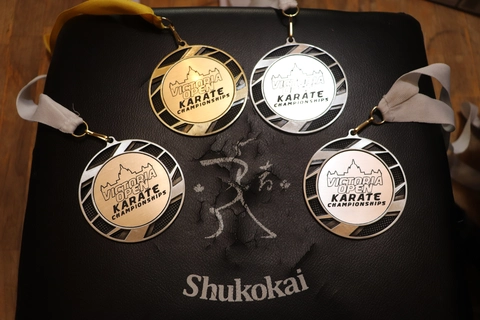 3 silver and 1 gold medal from Victoria Open Karate Tournament (2022) on a black impact pad with Shukokai written in white letters under a stick figure